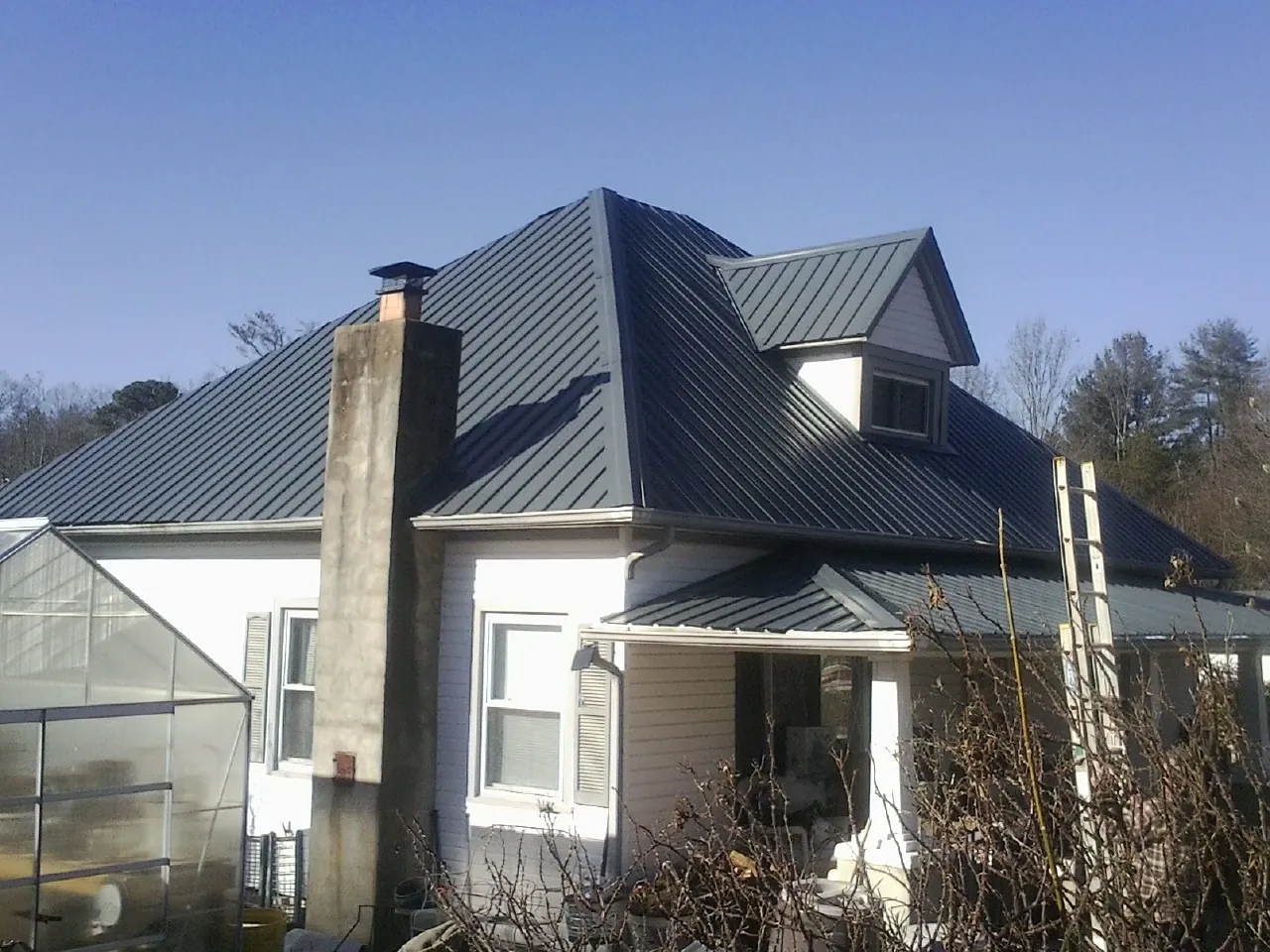 Dark blue standing seam metal roof on a white farmhouse with dormer — Slate & Tile Roof Repair by Roofing Brothers in Glenpool