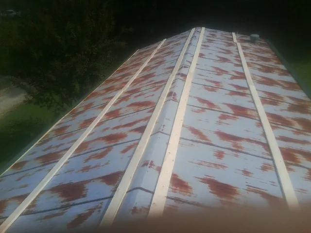 Rusted metal roof panels with new wood purlins before replacement — Storm Damage Roof Repair in Glenpool by Roofing Brothers