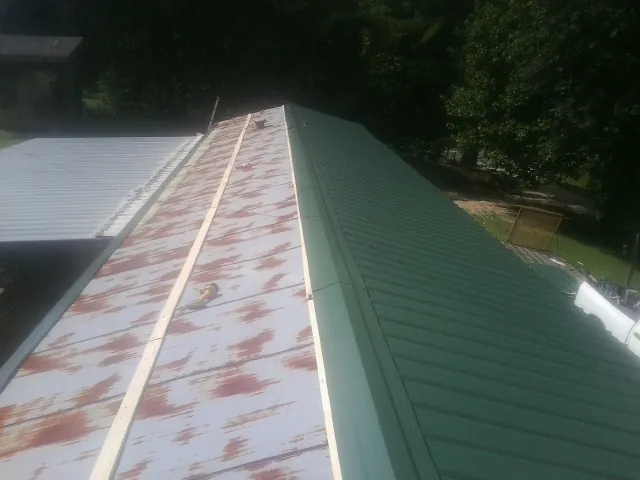 Old rusted panels beside newly installed green metal roofing — Wind Damage Roof Repair by Roofing Brothers in Glenpool