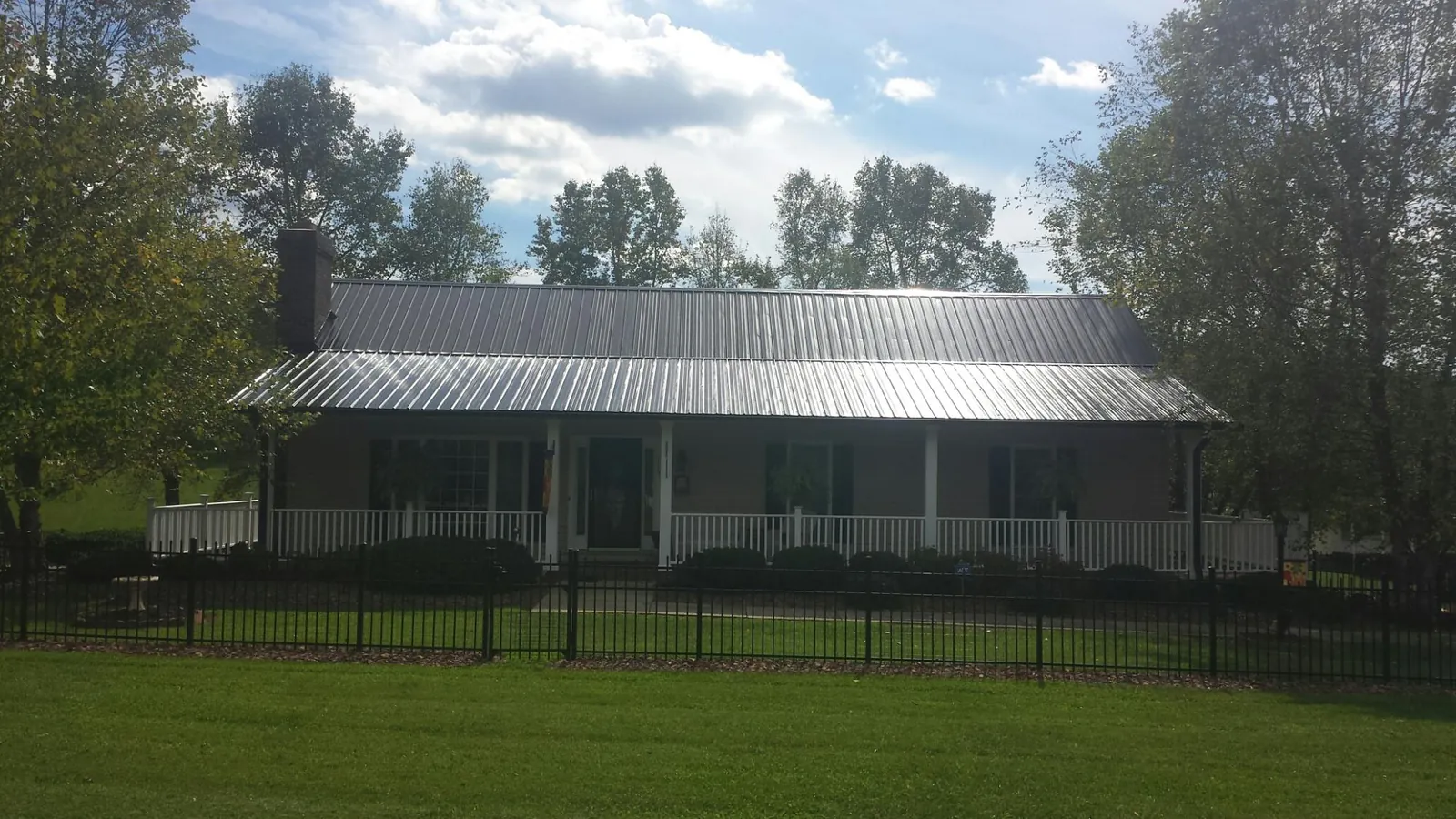 Gray metal roof on a brick ranch with a full width front porch — Gutter Guard Installation work by our crew in Glenpool