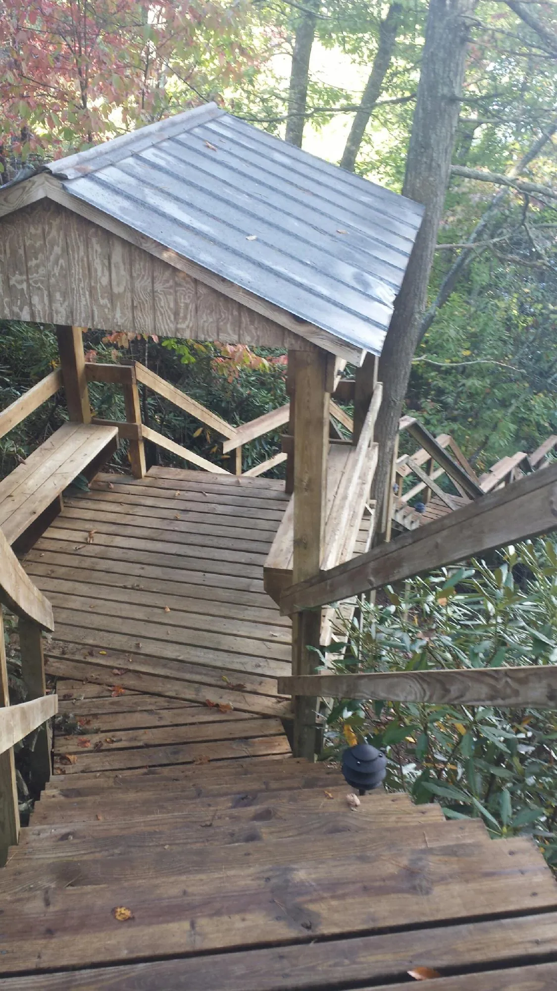 Metal roofed shelter over wooden steps on a wooded walkway — Skylight Repair & Installation work by our crew in Glenpool